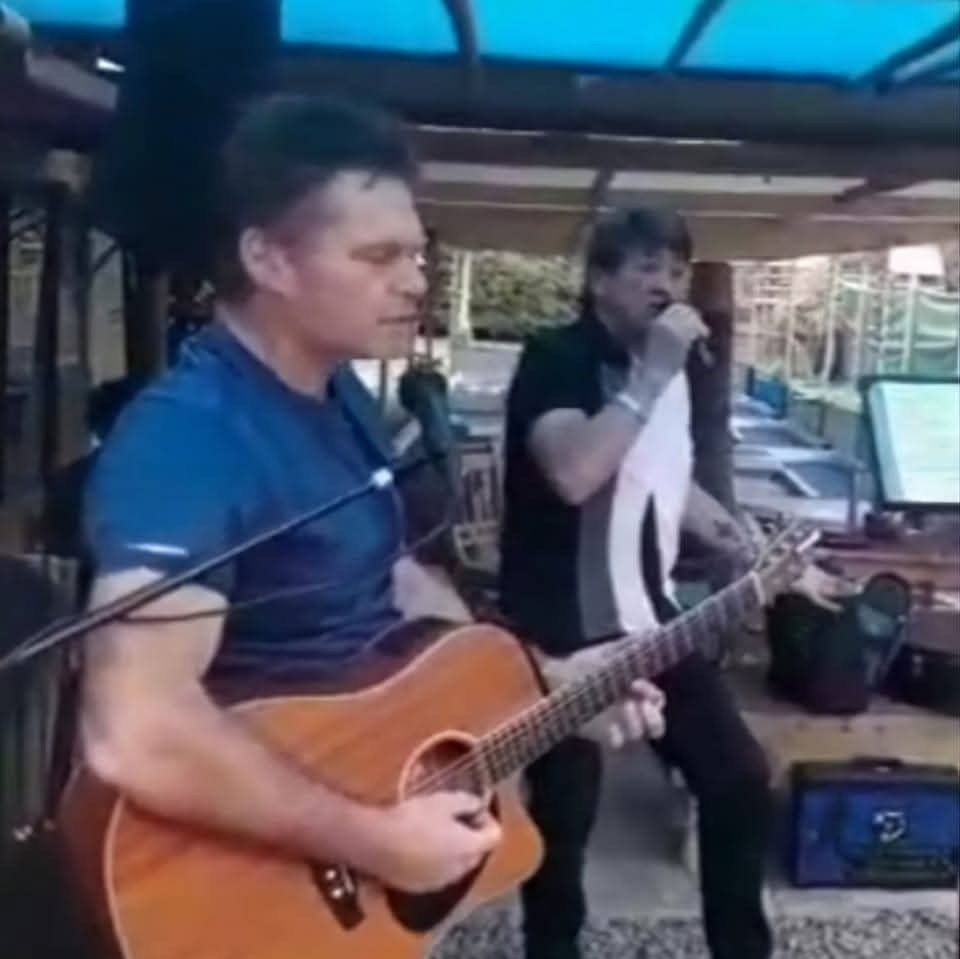 Murphy performing acoustic guitar with another singer