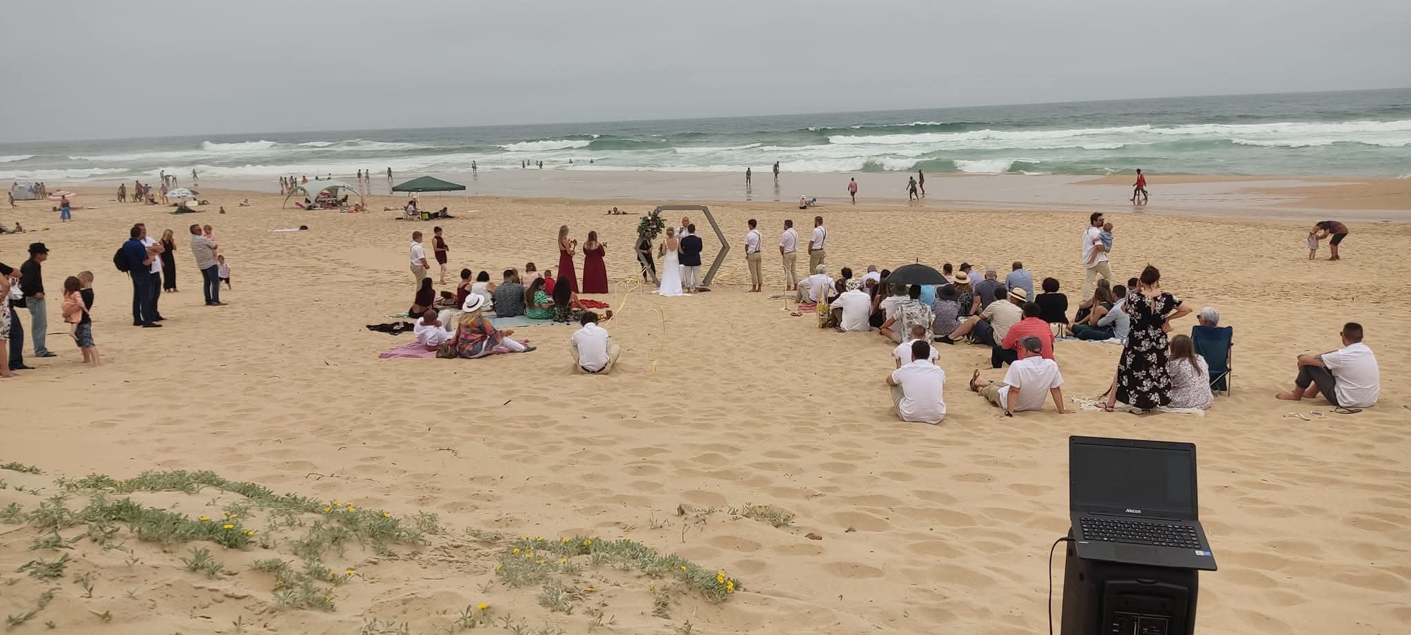 Beach wedding ceremony with guests and ocean backdrop