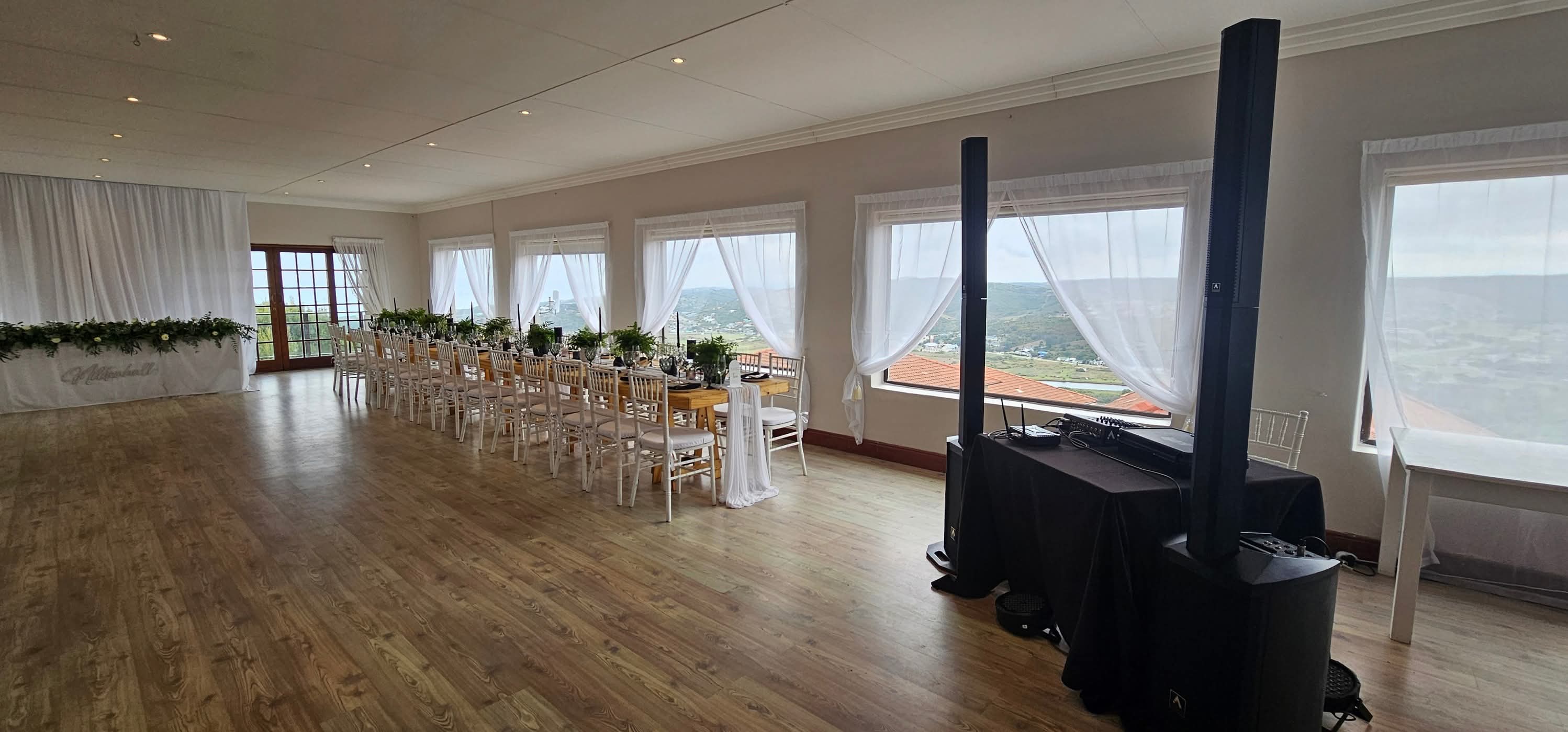 Bright wedding reception hall with speaker columns and DJ table