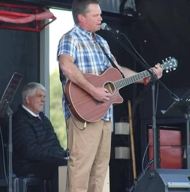 Murphy singing and playing acoustic guitar on stage