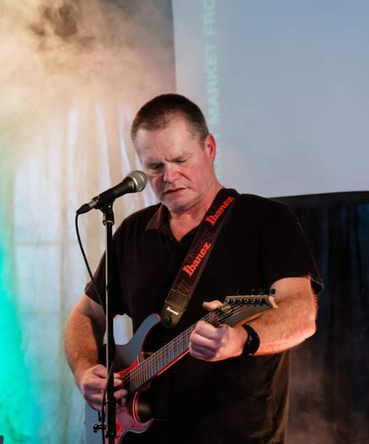 Murphy performing live on electric guitar under stage lights