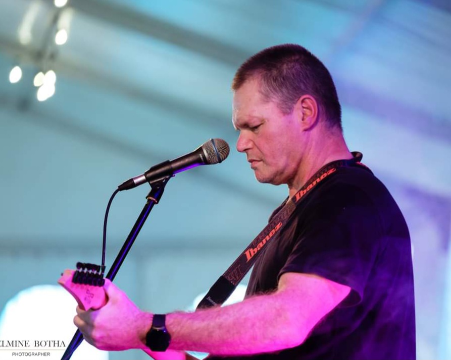 Murphy playing electric guitar in side profile during a live show
